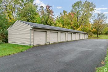 A long garage with a metal roof is surrounded by trees.